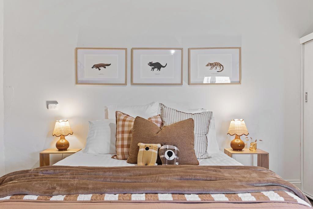 A bedroom with a bed, pillows, a blanket, and framed animal pictures on the wall.