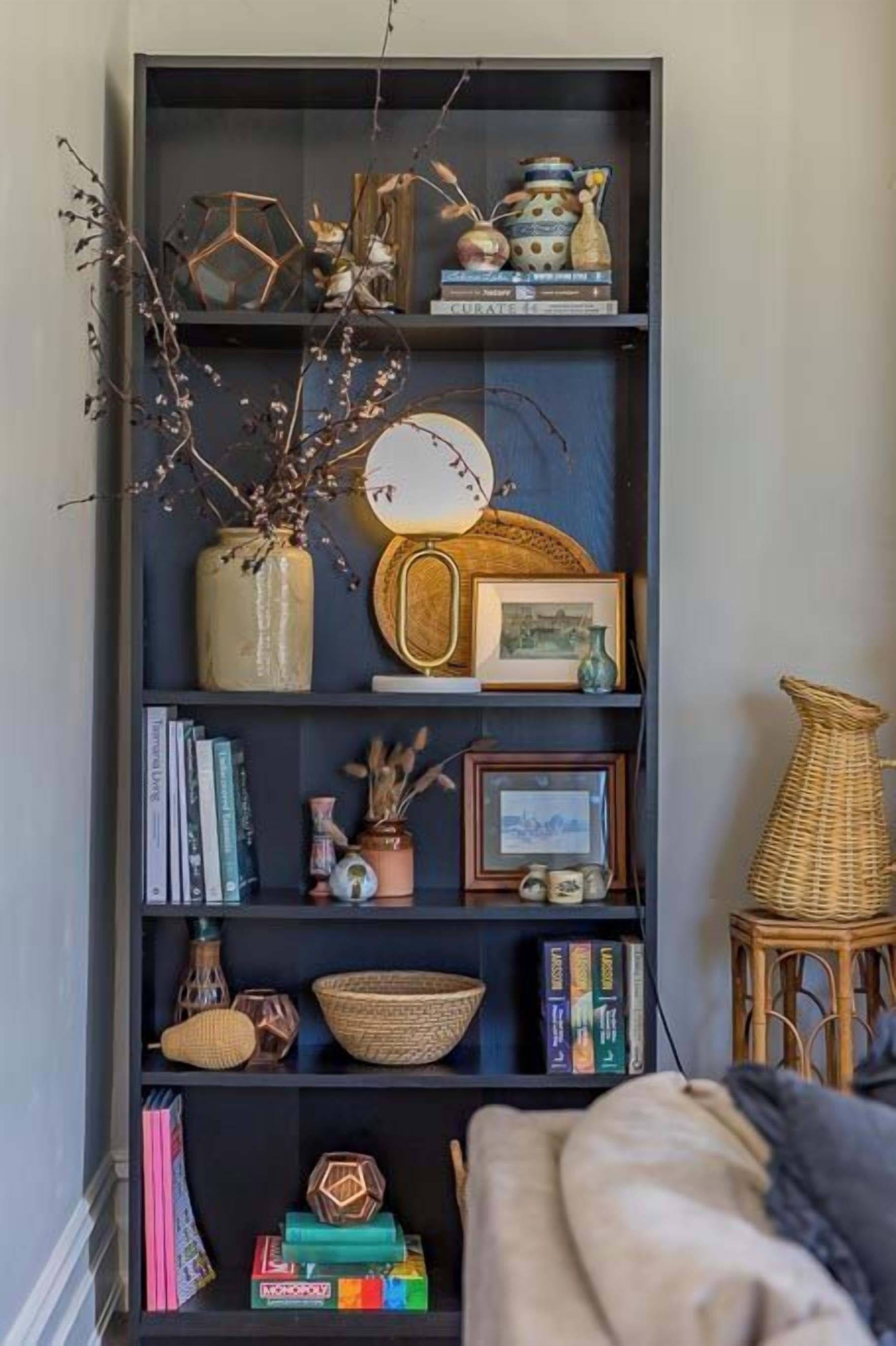 A bookshelf with various decorative items, including books, vases, and a wicker chair.