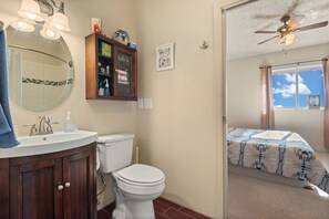Ein Badezimmer mit Toilette, Waschbecken und Schrank, sowie ein Schlafzimmer mit Bett und Fenster.