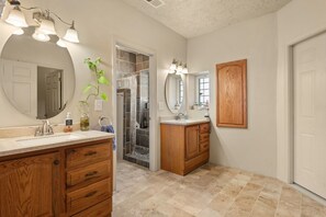 Une salle de bain avec un meuble-lavabo en bois, un grand miroir et un espace douche.