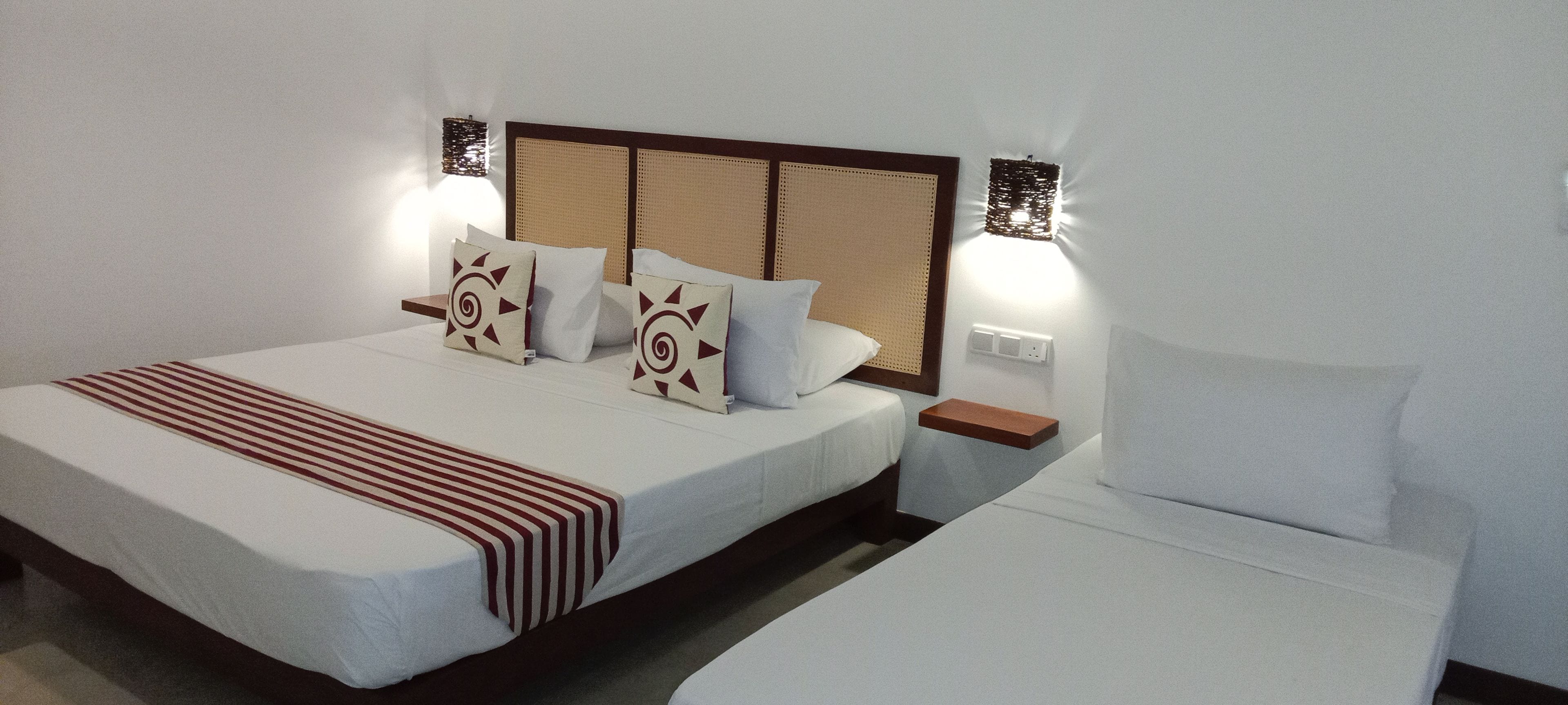 Una cama doble con una colcha a rayas, dos almohadas con diseño geométrico y una mesita de noche con lámpara.