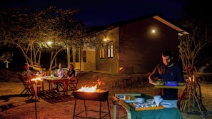 An outdoor dining area with a barbecue grill, tables, and chairs.