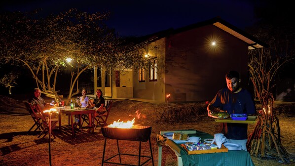An outdoor dining area with a barbecue grill, tables, and chairs.