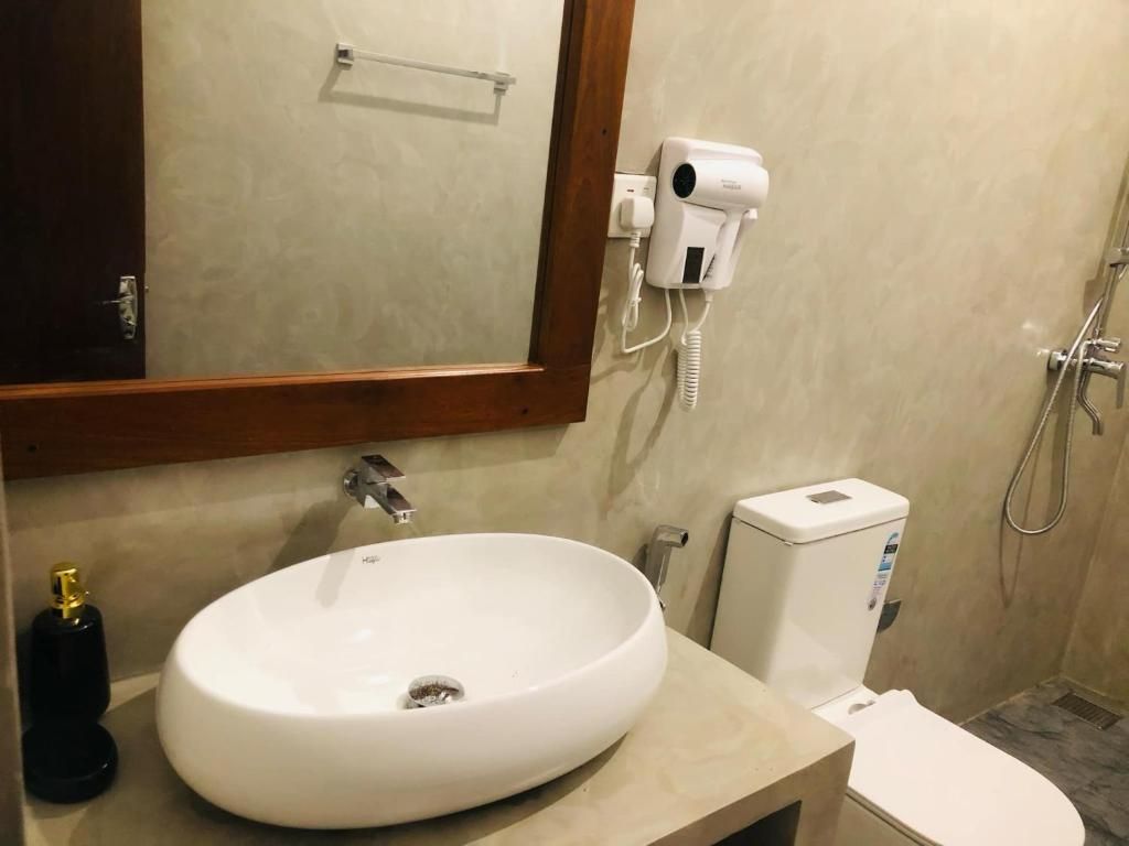 A bathroom with a white sink, a mirror, a hairdryer, and a toilet.