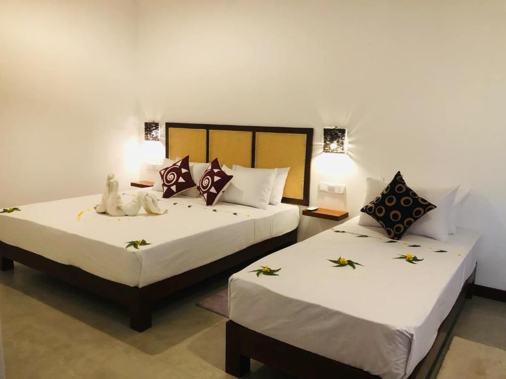 Ein Hotelzimmer mit zwei Einzelbetten, jeweils mit weißer Bettdecke und Dekokissen. An den Nachttischen stehen Lampen, und an der Wand ist eine Leuchte angebracht.
