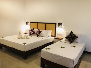 A hotel room with two single beds, each with a white bedspread and decorative pillows. There are bedside tables with lamps and a wall-mounted light fixture. - Wild Loch Yala (Yala)