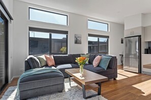 Ein modernes Wohnzimmer mit einer Eckcouch, einem Couchtisch und Blick zur Küche.
