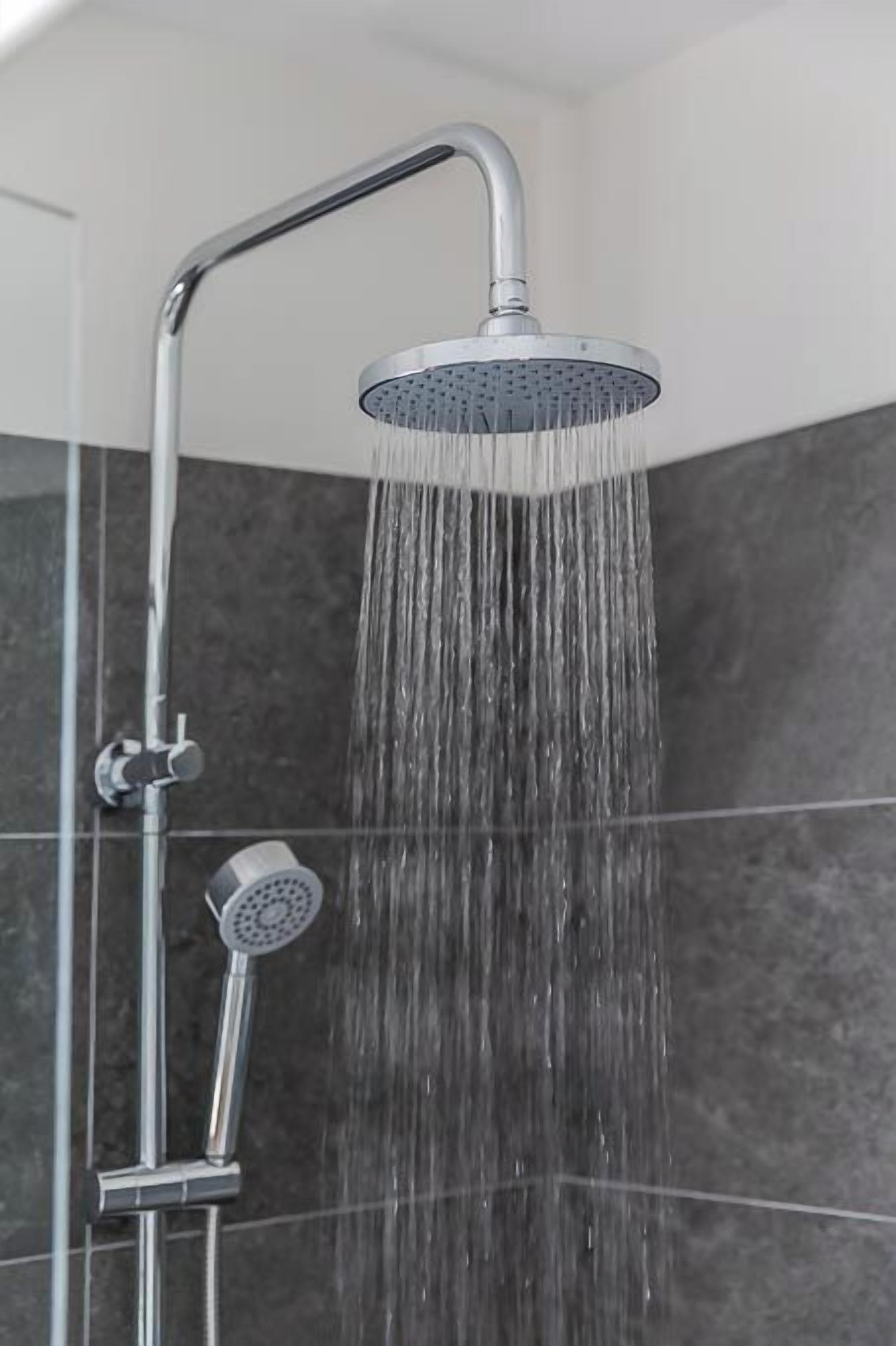 Een douchekop met stromend water, een handdouche en een douchekop bevestigd aan de muur.