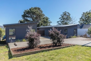 A modern two-story residential building with a flat roof, a covered patio area, and a landscaped garden with shrubs. - Pioneer's Rest - two homes at Branxholm, near Derby (Branxholm)