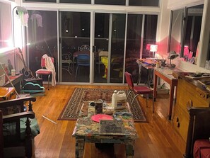 A room with a dining table, chairs, a window, and a view of the outside. - Artists home above rainforest sleeps 10 with pool (Tamborine Mountain)