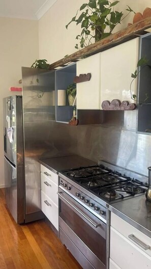 A kitchen with stainless steel appliances, a gas stove, and wooden cabinets. - Artists home above rainforest sleeps 10 with pool (Tamborine Mountain)