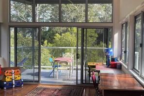 A room with a sliding glass door leading to an outdoor balcony with a hammock, chairs, and a table. - Artists home above rainforest sleeps 10 with pool (Tamborine Mountain)
