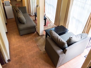 A room with a sofa, a small table, and a rug. There is a window with curtains. - Rosslyn Apartments (Nairobi)