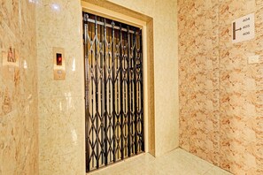 Un ascensor con una verja de metal, una pared de mármol y un cartel con números.