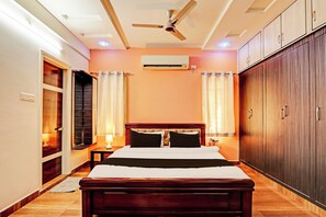 Una habitación de hotel con cama, ventilador de techo, equipo de aire acondicionado y armario.