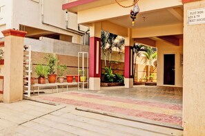Entrada de un hotel con piso de baldosas, plantas en macetas y un cartel que indica las parcelas 78 y 79.
