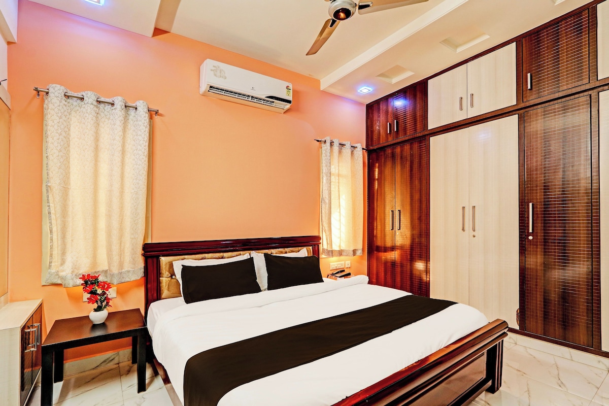 Una habitación de hotel con cama, mesitas de noche, aire acondicionado, armario y ventilador de techo.