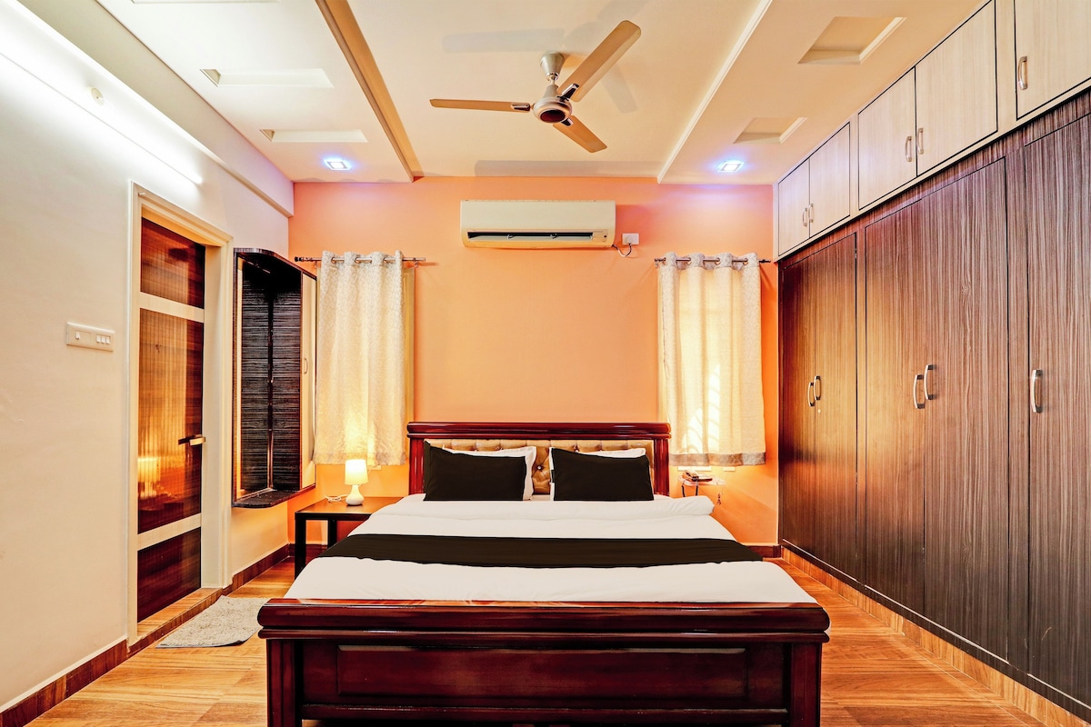 Una habitación de hotel con una cama, un ventilador de techo, un equipo de aire acondicionado y un armario.