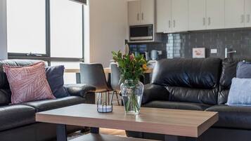 A modern living room with a leather sofa, a wooden coffee table, and a vase with flowers.
