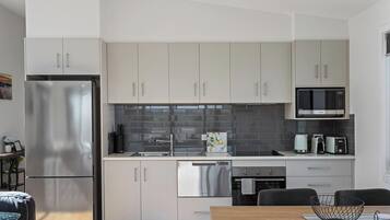 Una cocina moderna con electrodomésticos de acero inoxidable, armarios blancos y salpicadero de azulejos.