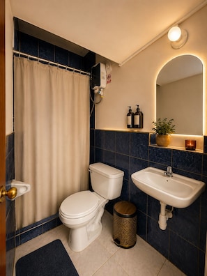 A bathroom with a toilet, sink, and shower curtain. - Hotel Colonial Cusco (Wanchag)