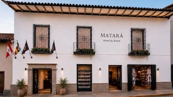 Un hotel con fachada blanca, varios balcones con barandillas de hierro forjado y un cartel que dice 'Matará Hotel By Ámak'.
