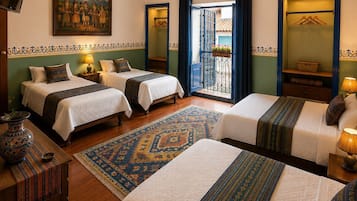 Habitación de hotel con tres camas, un televisor, un cuadro y un balcón con vistas.