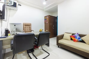 Escritório em casa com uma mesa, duas cadeiras, um laptop, um monitor de computador e um armário com chaves.