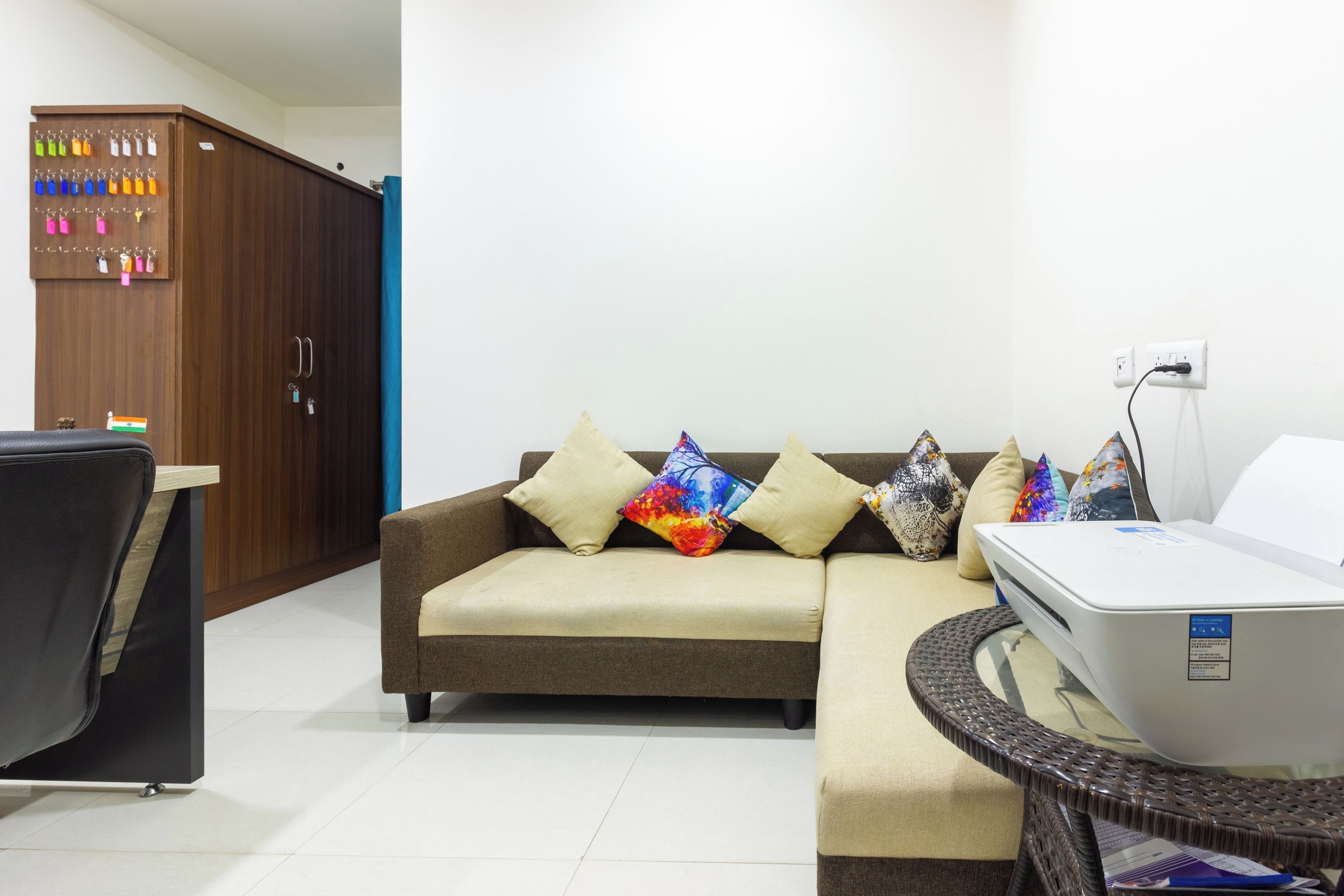 A living room with a sofa, a small table, a cabinet with keys, and a power outlet.