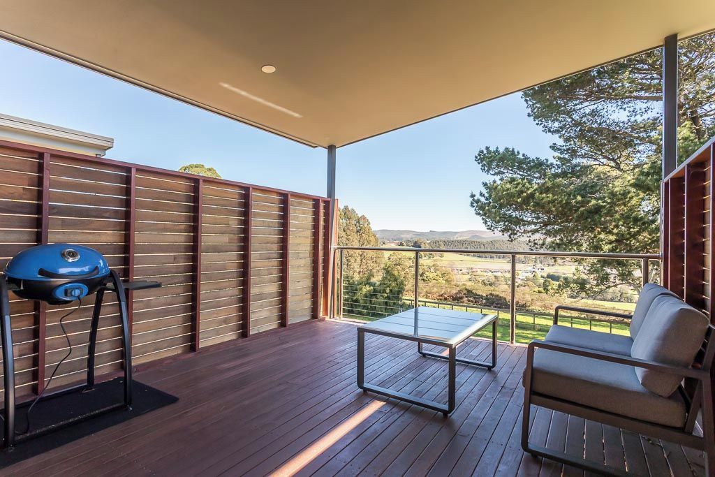 Een balkon met een barbecue, een tafel en een bank.