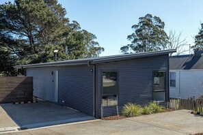 A modern single-story building with a metal exterior, a garage door, and a small window.