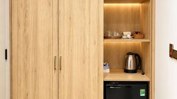 Cocina compacta con muebles de madera, lavavajillas negro y repisas con utensilios de cocina.