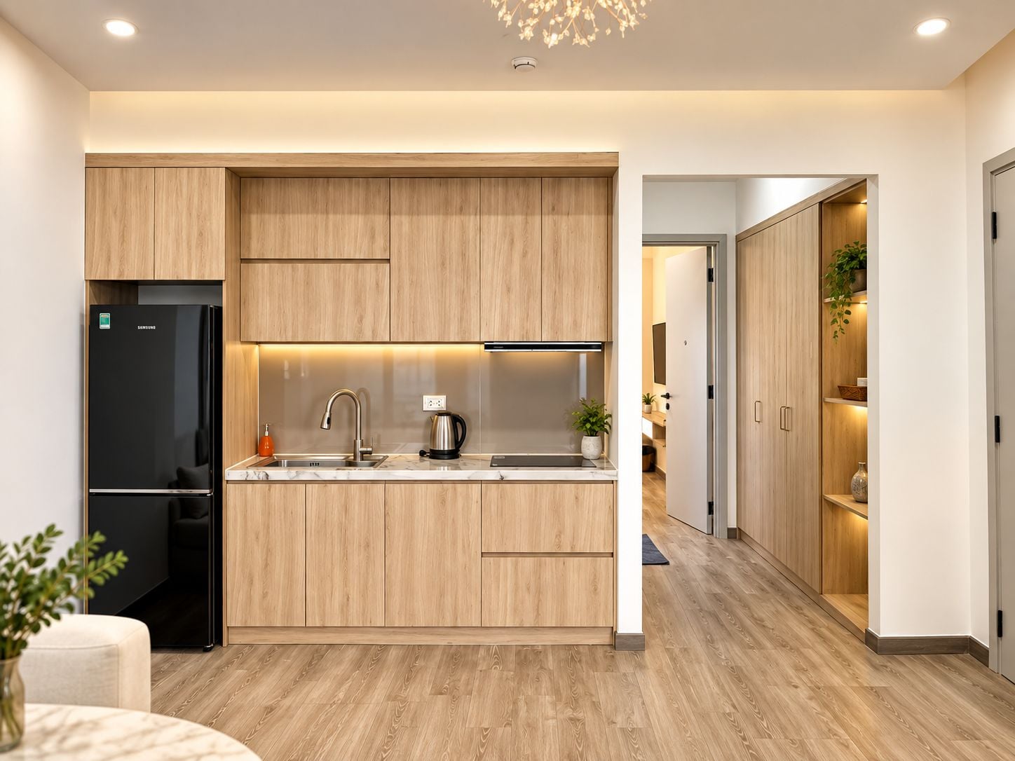 Une cuisine moderne avec des meubles en bois, un réfrigérateur noir et un four encastré.