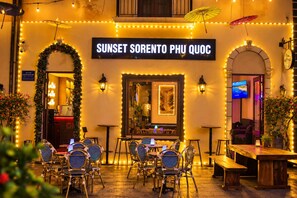 An outdoor seating area with tables and chairs, a sign reading 'SUNSET SORENTO PHU QUOC', and decorative lights. - Sunset Sorento Hotel & Apartment PhuQuoc (Phu Quoc)