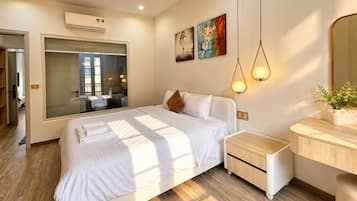 Una habitación de hotel moderna con una cama grande, mesitas de noche, un espejo, obras de arte en la pared y una lámpara en el techo.