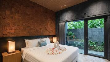 A modern bedroom with a stone wall, a large bed with white bedding, a swan-shaped decoration, and a view of greenery through a sliding door.