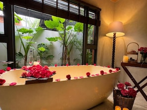 A bathtub with rose petals and a candle, a lamp, and a basket of roses. - Flowering villa (Liuqiu)