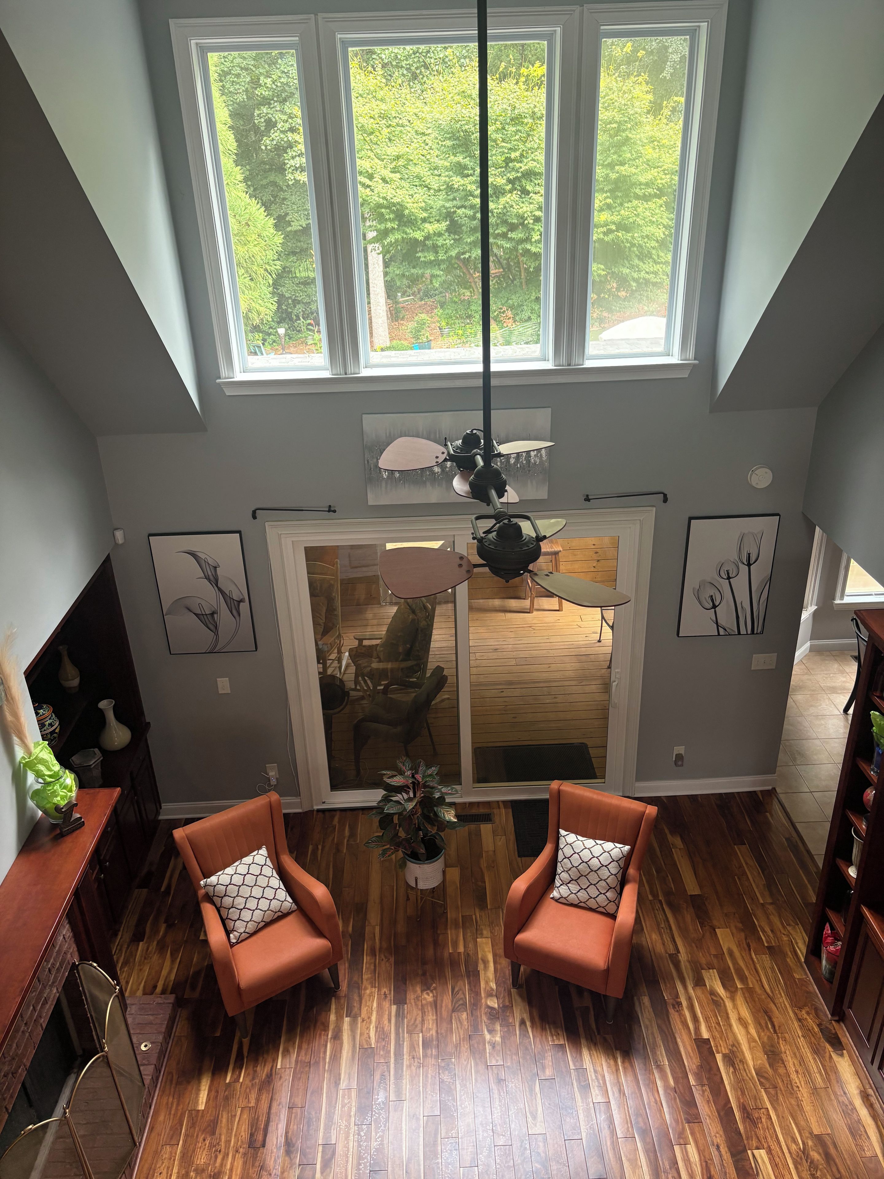 A spacious room with a high ceiling, large windows, and a wooden floor.