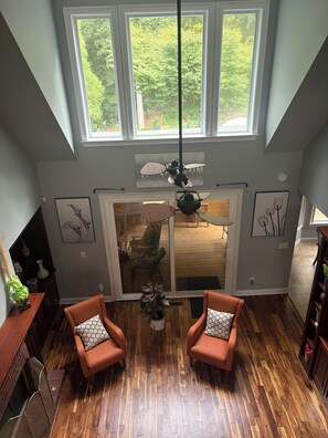A spacious room with a high ceiling, large windows, and a wooden floor.