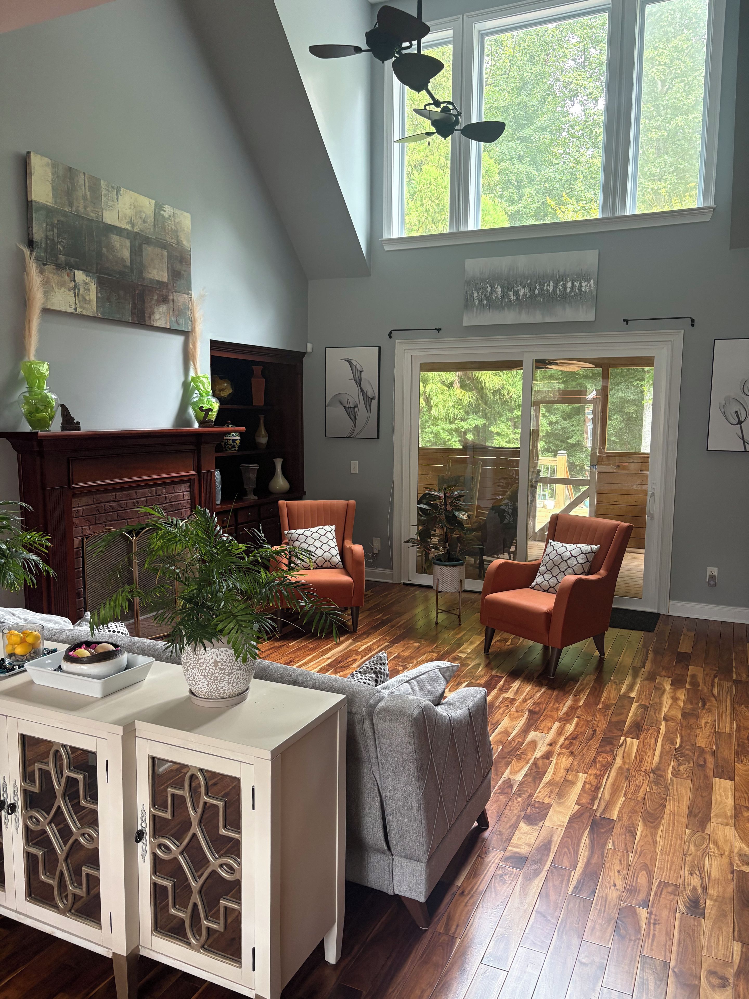 A spacious living room with a fireplace, two armchairs, a sofa, and a dining area.