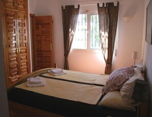 A bedroom with a bed, a wardrobe, and a window with curtains. - Holiday Home in Torrox With Swimming Pool (Torrox)