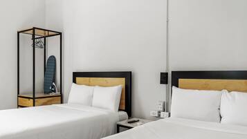 Ein Hotelzimmer mit zwei Betten, einem Kleiderschrank, einem Nachttisch und einem Wandheizkörper.