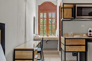 Una cocina pequeña con ventana, un lavamanos y un microondas.