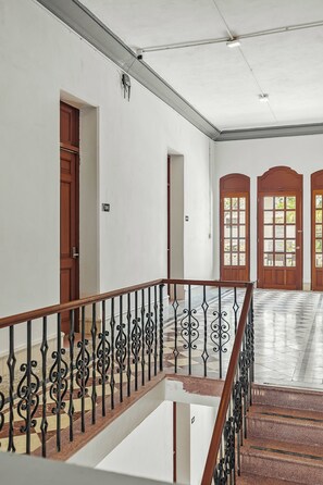 A staircase with a wooden handrail and black metal balusters leading to a landing.