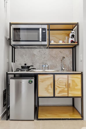 Una cocina compacta con microondas, estufa, refrigerador y armarios de madera.