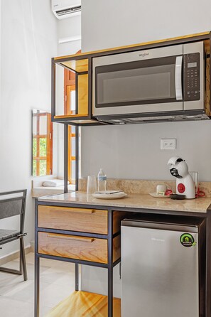 A compact kitchenette with a microwave, a small refrigerator, and a coffee maker.