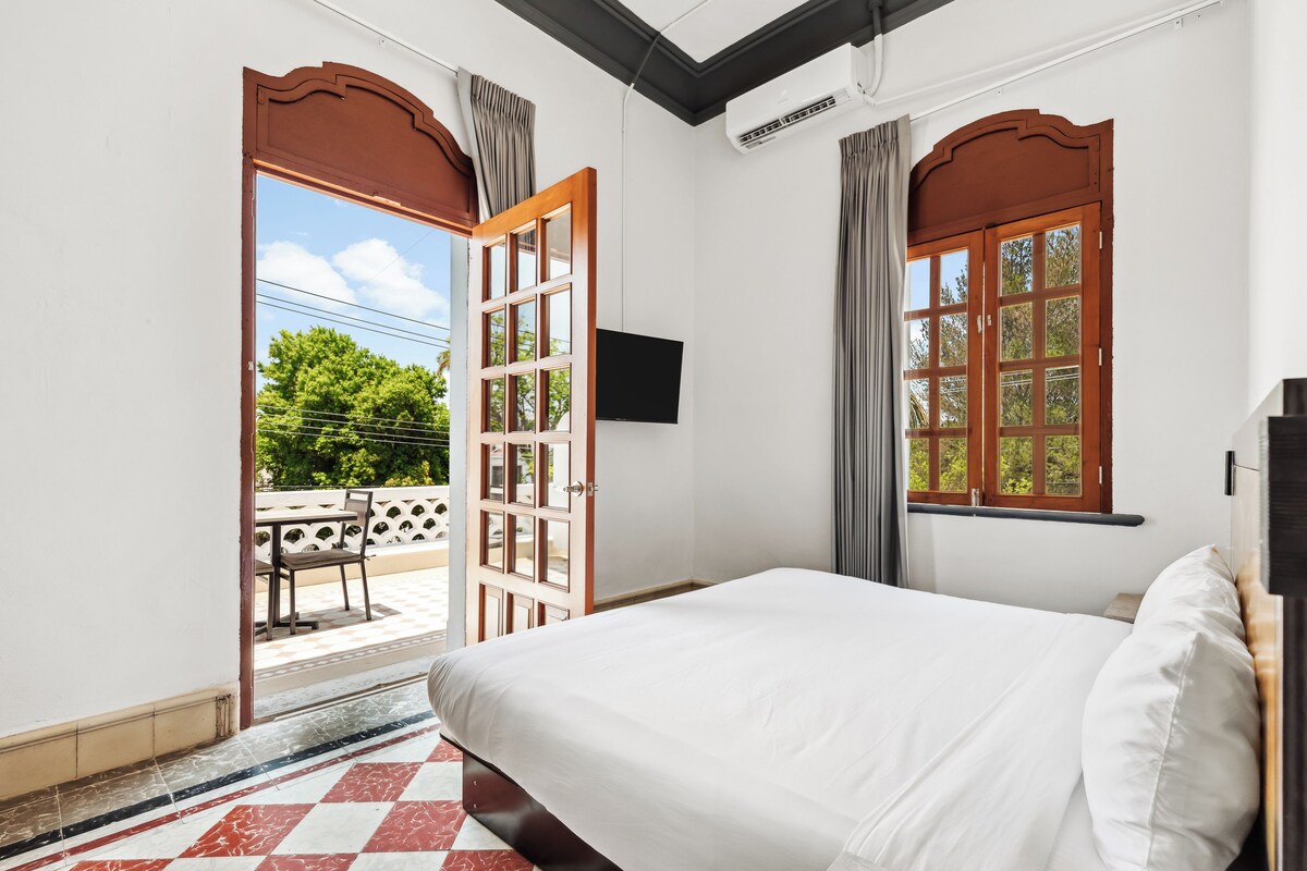 Una habitación de hotel con cama, televisión y vistas al exterior.