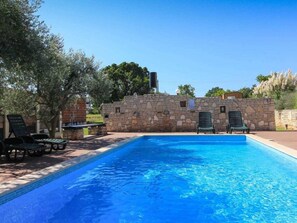 A swimming pool with a stone wall and lounge chairs. - Holiday Home in Pavicini With Swimming Pool (Marcana)
