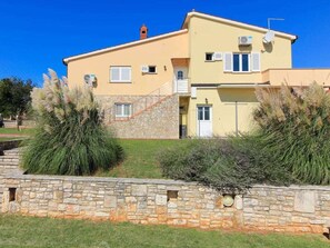 A two-story building with a stone wall in front, a flat roof, and a clear blue sky. - Holiday Home in Pavicini With Swimming Pool (Marcana)