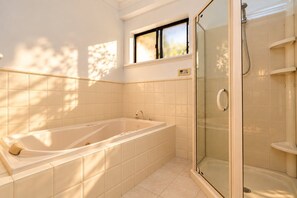 A bathroom with a bathtub, a glass-enclosed shower, and a window. - Spacious 3-Bedroom Marion Home | Alfresco Living | Table Tennis (Marion)
